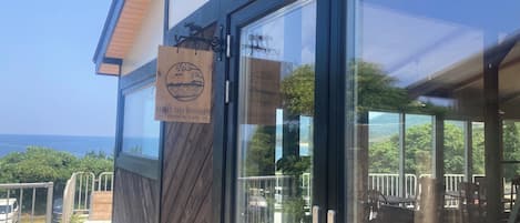 A hotel entrance with a view of the ocean, a wooden exterior, and a glass door.
