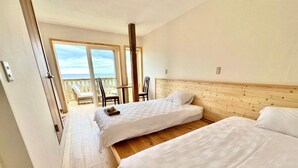 A hotel room with two beds, a wooden headboard, and a balcony with chairs. - umi no tonari hotel & cafe (Kyotango / Tango/ Taiza)
