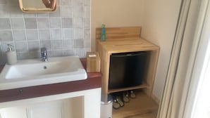 A bathroom with a white sink, a mirror, a wooden shelf with a black appliance, and a pair of slippers on the floor. - umi no tonari hotel & cafe (Kyotango / Tango/ Taiza)