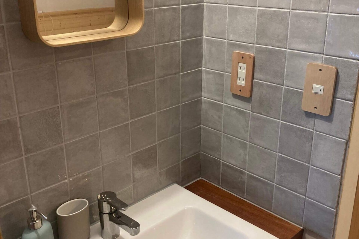 Un baño con un lavabo blanco, un espejo y dos enchufes en la pared.