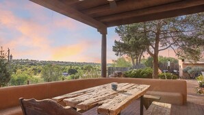 Eine Terrasse im Freien mit einem rustikalen Holztisch und Bänken, mit Blick auf eine schöne Landschaft.