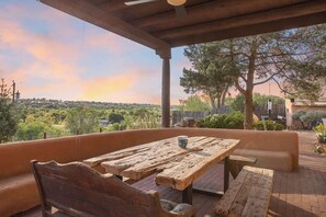 An outdoor patio with a rustic wooden table and benches, overlooking a scenic landscape. - 1795 Adobe, Dog Friendly · High Road to Taos (Ranchos de Taos)