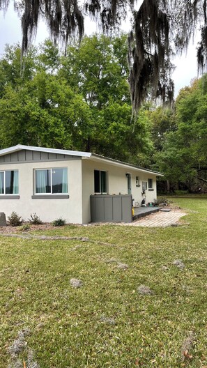 A single-story house with a flat roof, a front porch, and a small yard with grass and a paved area. -  Newly remodeled Serene 3-bedroom home in Crescent City (Crescent City)