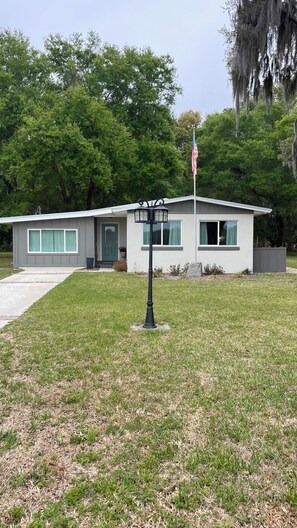 A single-story house with a front porch, a flagpole with an American flag, and a well-maintained lawn. -  Newly remodeled Serene 3-bedroom home in Crescent City (Crescent City)