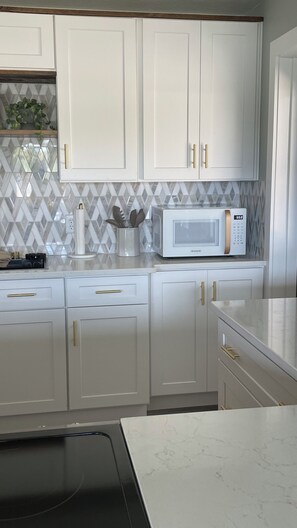 A kitchen with white cabinets, a microwave, and a countertop with a plant and utensils. -  Newly remodeled Serene 3-bedroom home in Crescent City (Crescent City)