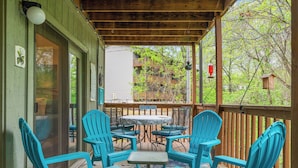 Un portico coperto con sedie e un tavolo blu, affacciato su un edificio con un balcone.