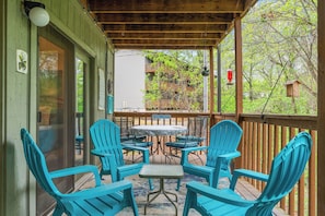 A covered patio with blue chairs and a table, overlooking a building with a balcony.