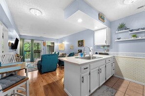 Une cuisine moderne avec des meubles blancs, un îlot central et un évier encastré.