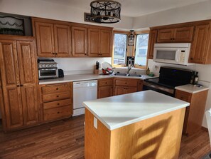 A kitchen with wooden cabinets, a dishwasher, a microwave, and a stove. - Charming Waterfront Retreat on the Mississippi River (Buffalo City)