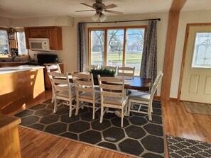 A kitchen with wooden cabinets, a microwave, and a dining area with a table and chairs. - Charming Waterfront Retreat on the Mississippi River (Buffalo City)
