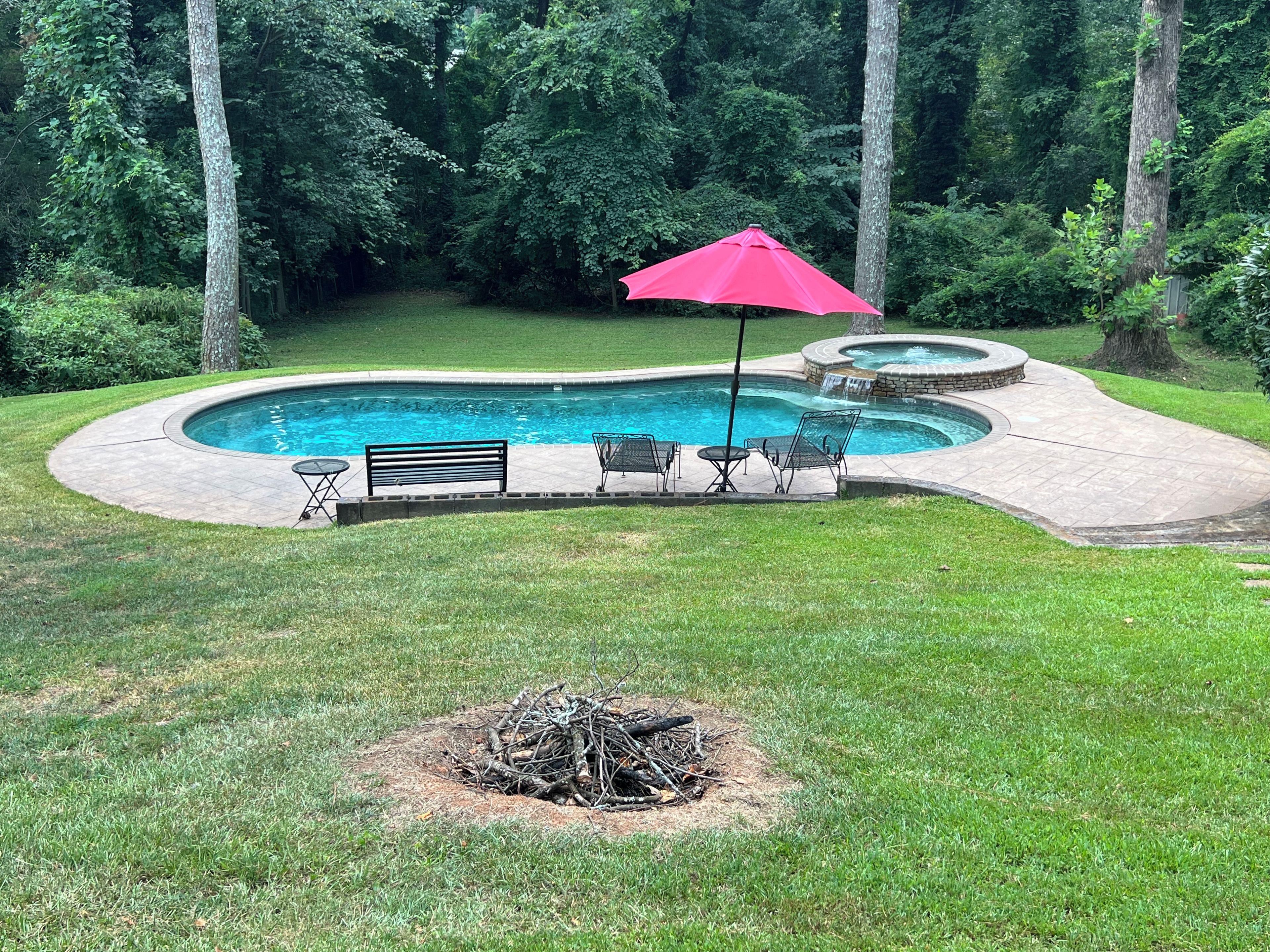 Un jardin avec une piscine, un foyer extérieur et du mobilier de jardin.