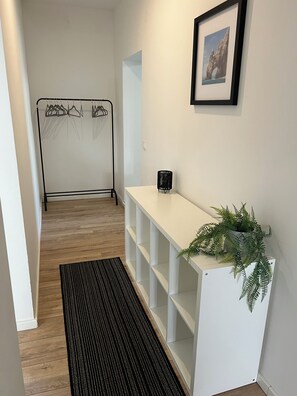 A hallway with a white console table, a black rug, and a hanging clothes rack. - Spacious ground-floor apartment with a terrace – 4 bedrooms for 6 guests (Bremerhaven)