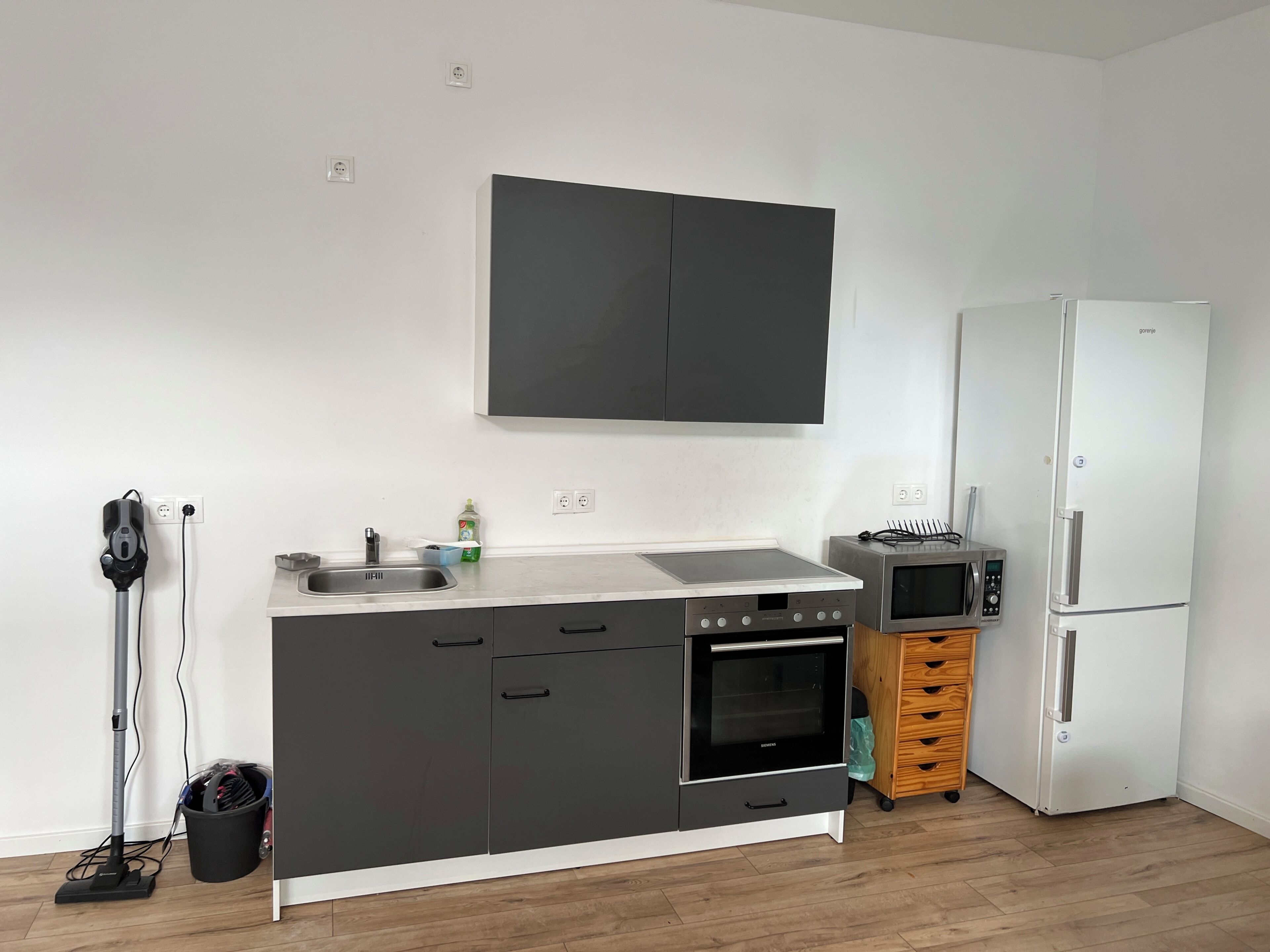 Eine kompakte Küche mit Einbauofen, Mikrowelle und Kühlschrank.