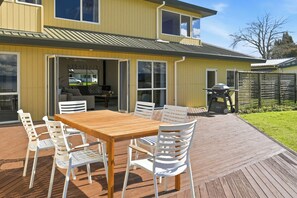 Una casa amarilla con un balcón, una parrilla y un patio con mesa y sillas.