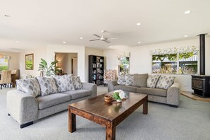 A modern living room with two sofas, a coffee table, a bookshelf, and a fireplace. - Shore Haven - Lakefront, Spa Pool, Sleeps 8 (Rotorua)