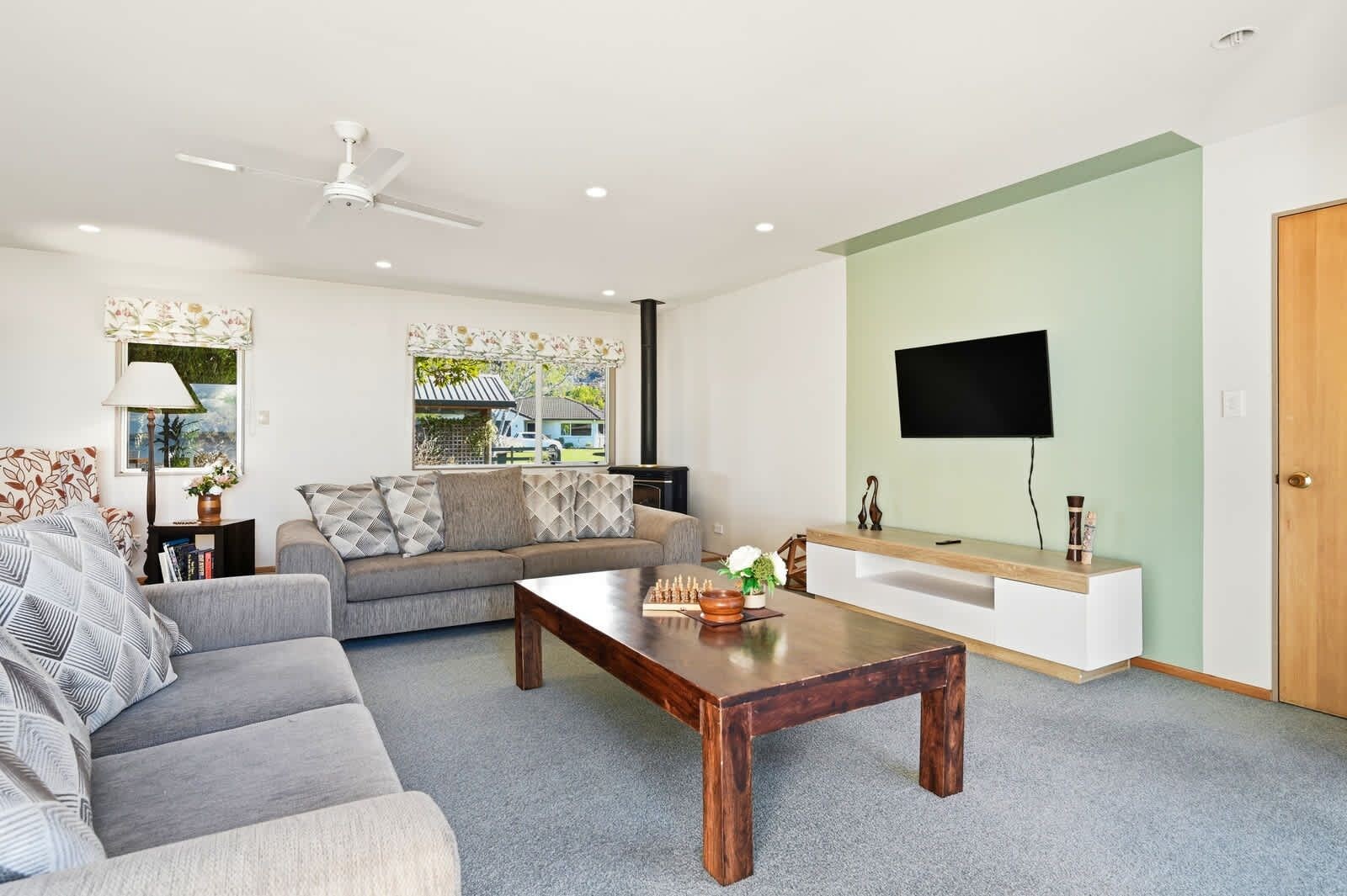 A modern living room with a sofa, coffee table, and a flat-screen TV mounted on the wall.