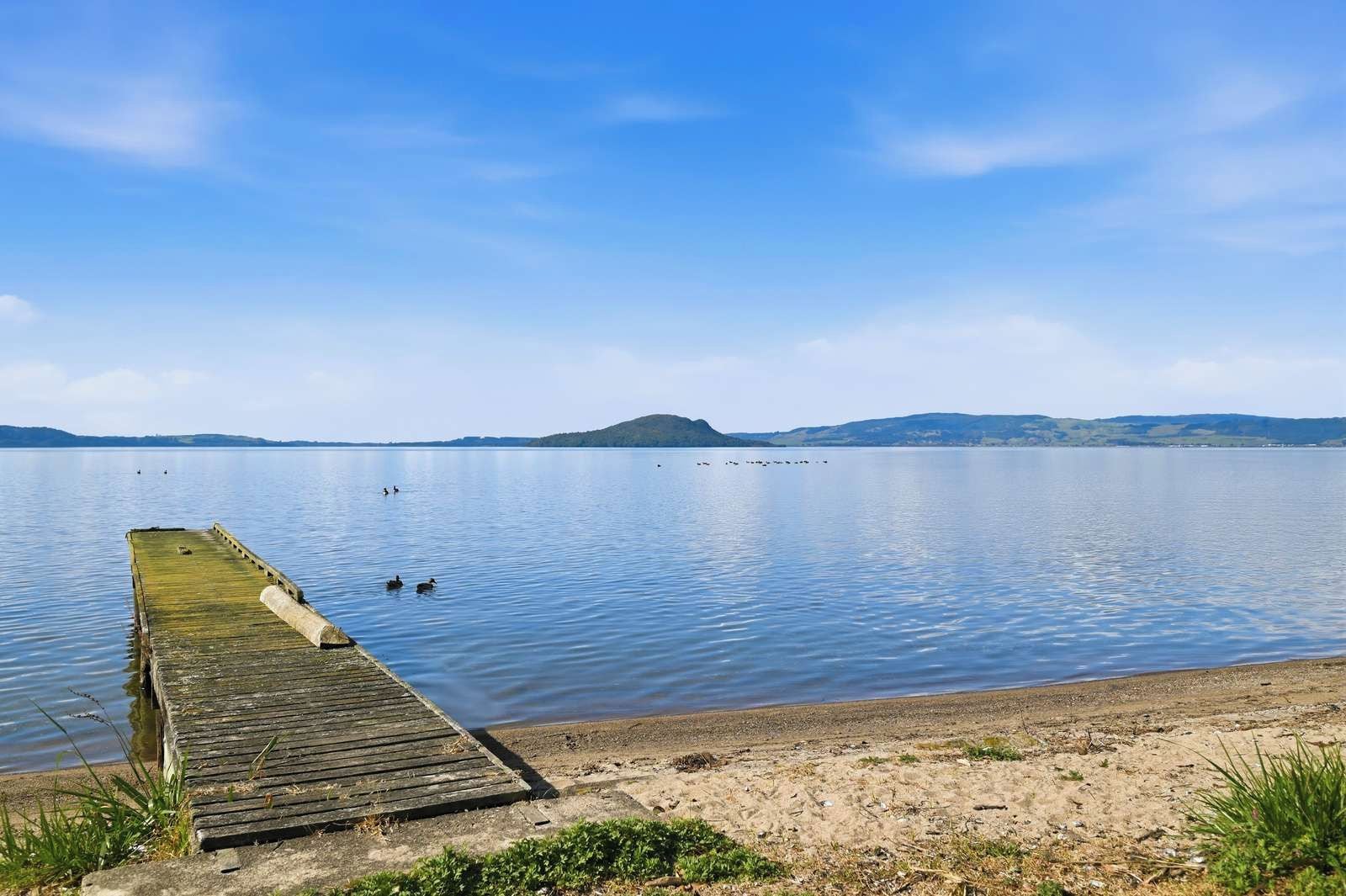 A wooden pier extending into calm water with a clear sky.