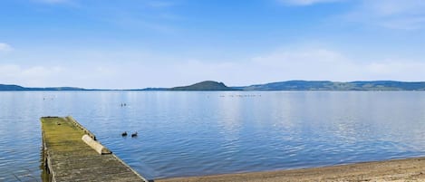 A wooden pier extending into calm water with a clear sky.