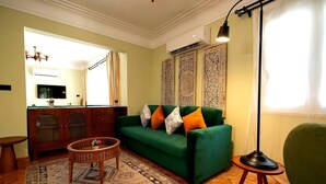 Un soggiorno con un divano verde, un tappeto decorato e un televisore appeso al muro.