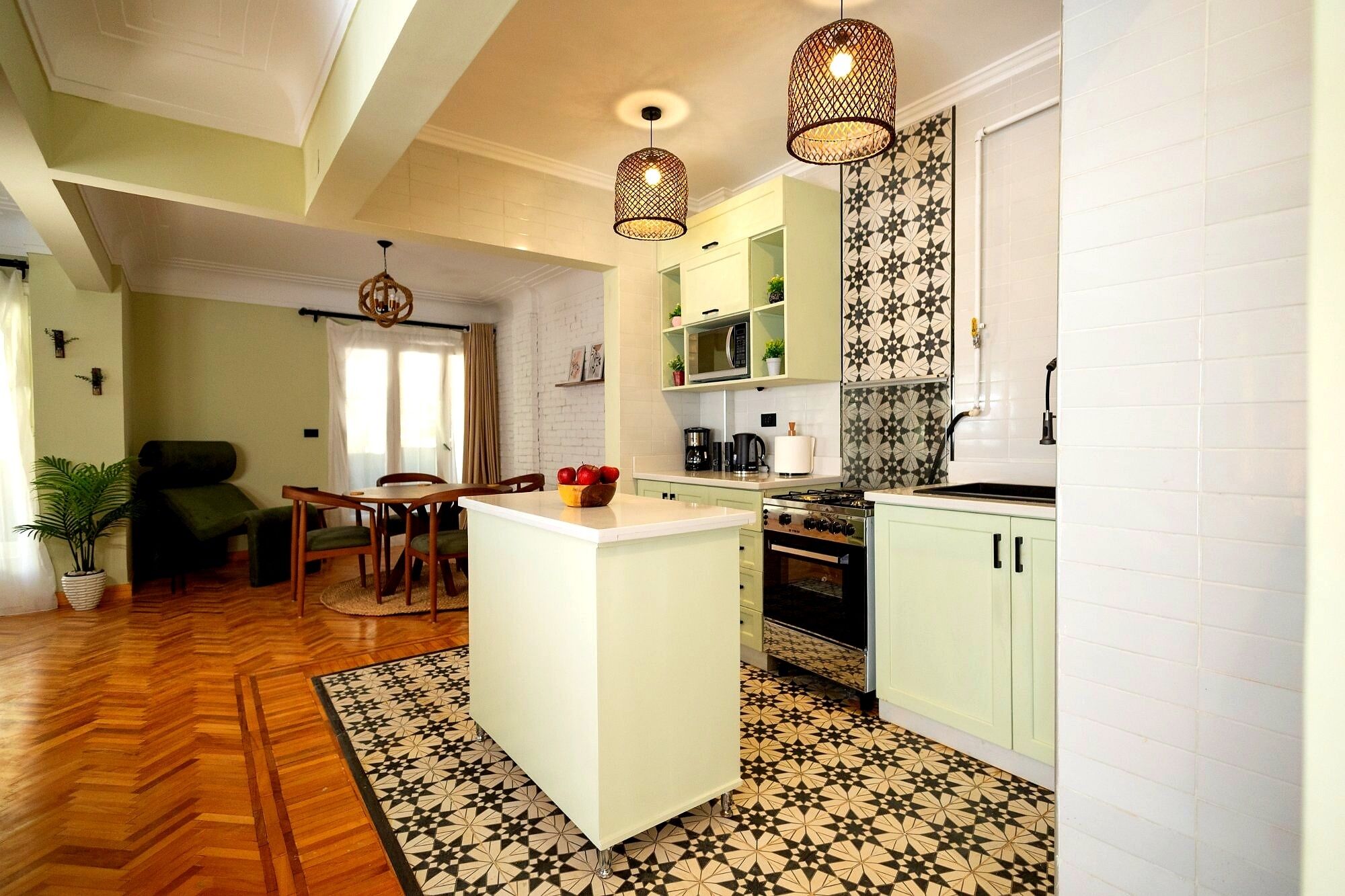 A modern kitchen with a central island, pendant lights, and patterned floor tiles.