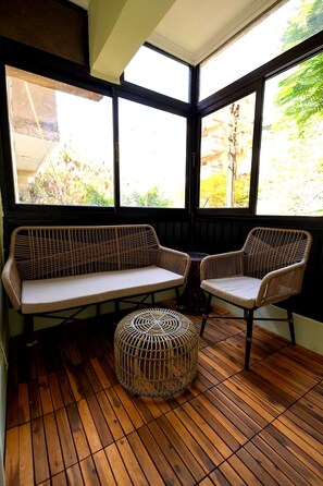 A room with a wooden floor, a sofa, two chairs, and a woven ottoman. - Heliopolis 2 Bedrooms Apartments with Huge Patio - 10 Minutes to Airport (Cairo Governorate)