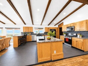 A modern kitchen with wooden cabinets, a central island, and a view of the outdoors. - Wild Montana Retreat | Hot Tub & Mountain Views (Eureka)