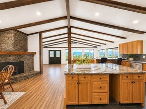 Une cuisine spacieuse avec des meubles en bois, un plan de travail en granit et une cheminée en pierre.