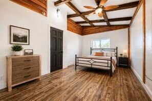 A bedroom with a bed, a dresser, a nightstand, a ceiling fan, and a window. - Wild Montana Retreat | Hot Tub & Mountain Views (Eureka)