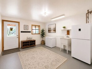 A compact kitchen with a refrigerator, sink, and a small window. - Wild Montana Retreat | Hot Tub & Mountain Views (Eureka)
