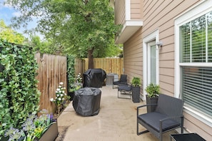 A covered patio area with outdoor furniture, a covered grill, and a wooden fence. - 2BR Home Near Augusta National & Medical District (Augusta)