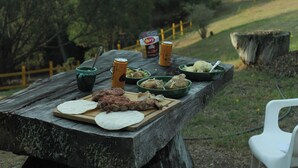 Ein Picknick mit Essen und Getränken auf einem Holztisch im Freien.