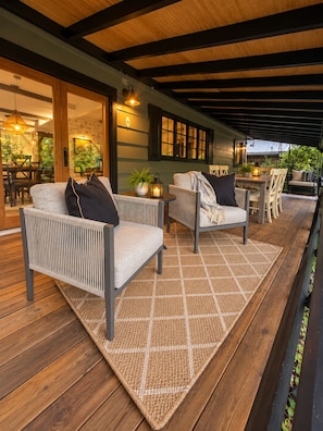 An outdoor patio with wicker furniture, a woven rug, and a wooden deck.