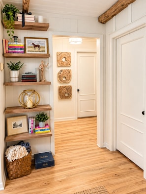 A hallway with wooden shelves, a door, and a woven rug.