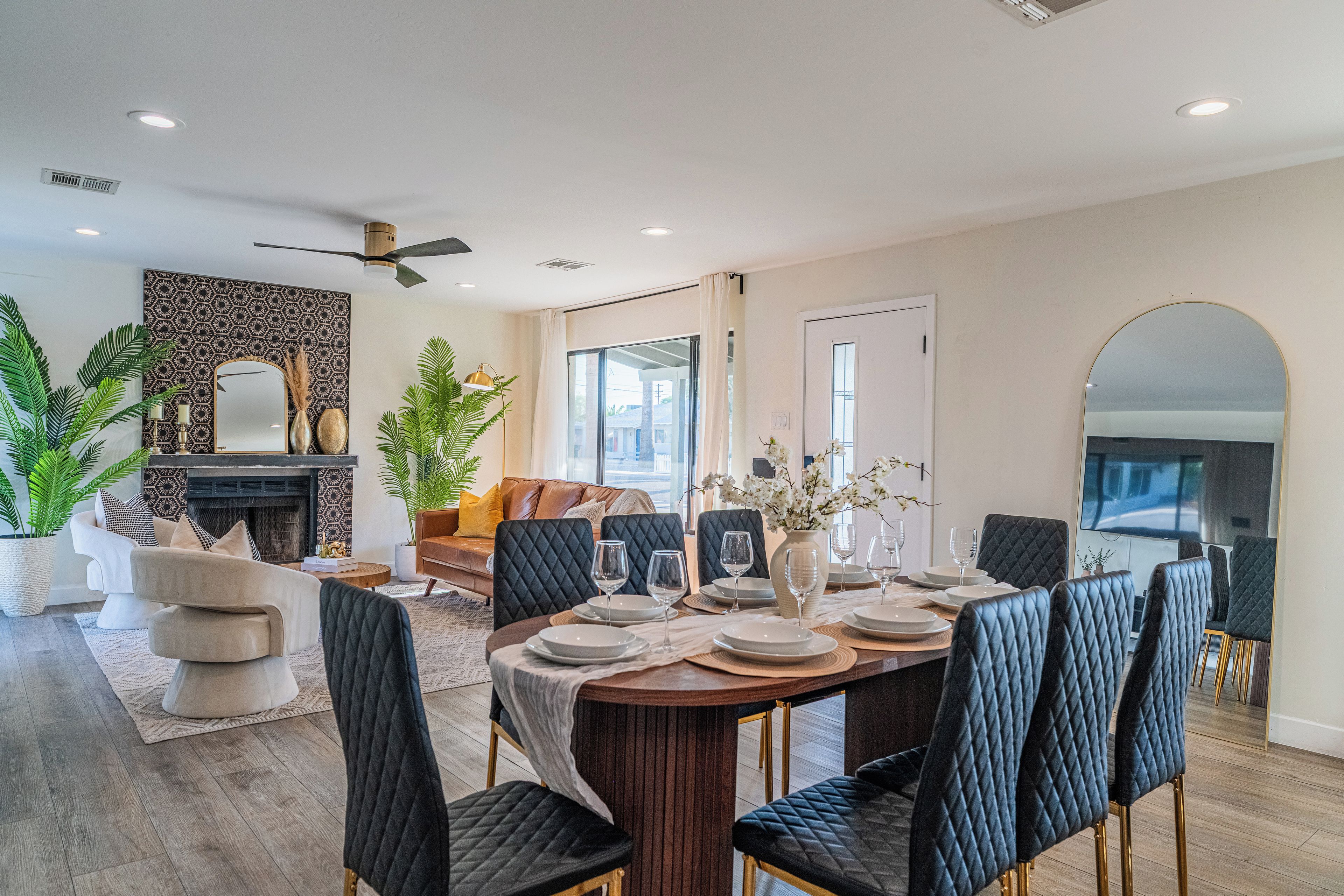 Un coin repas avec une table ronde dressée pour quatre personnes, entourée de chaises noires à revêtement capitonné et aux pieds dorés.
