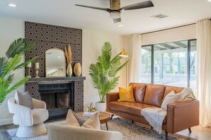 En moderne stue med pejs, sofa, sofabord og dekorative planter.