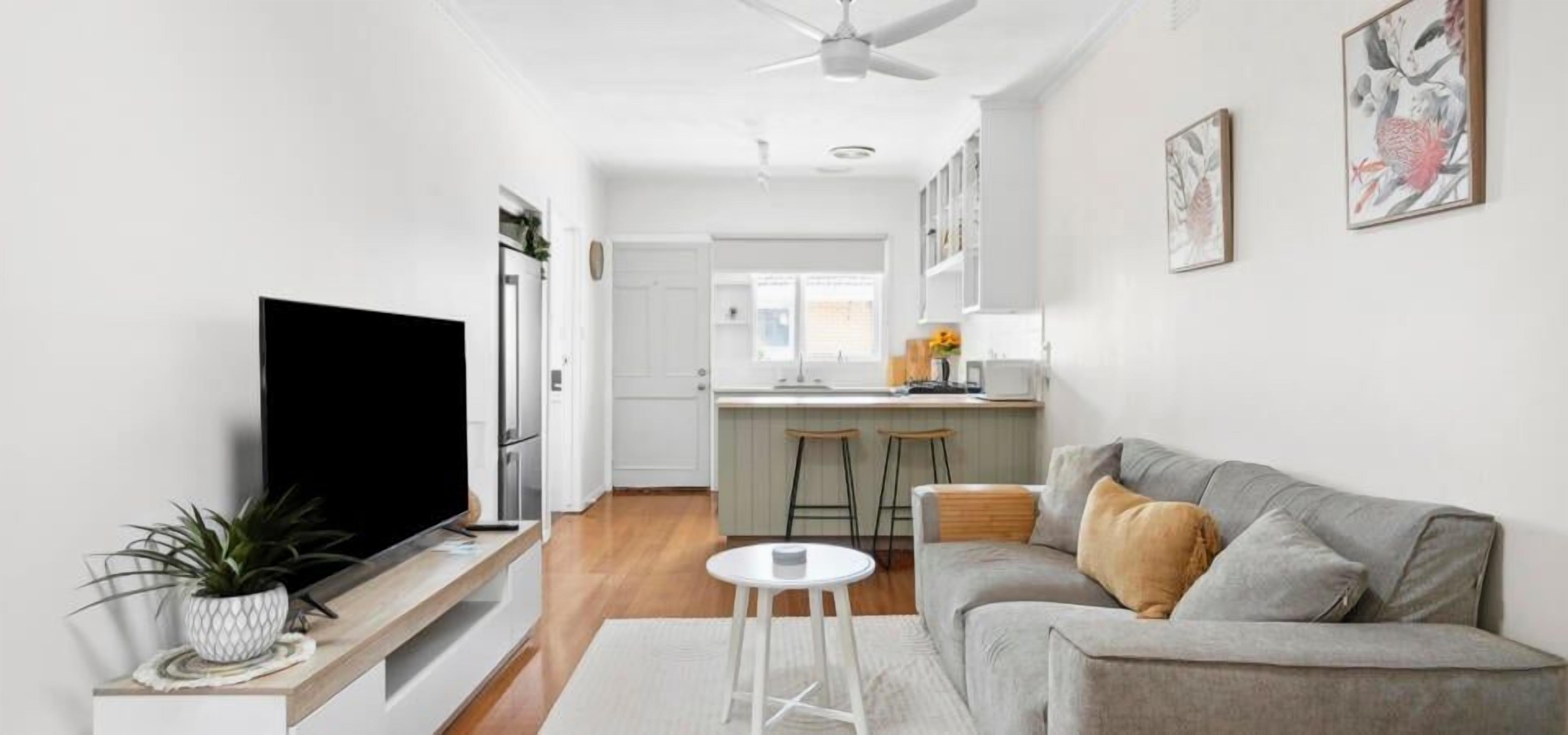 A modern living room with a grey sofa, a white coffee table, and a flat-screen TV.
