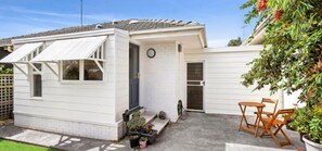 Ein Bungalow mit Terrasse, einer Tür und einem kleinen Garten.