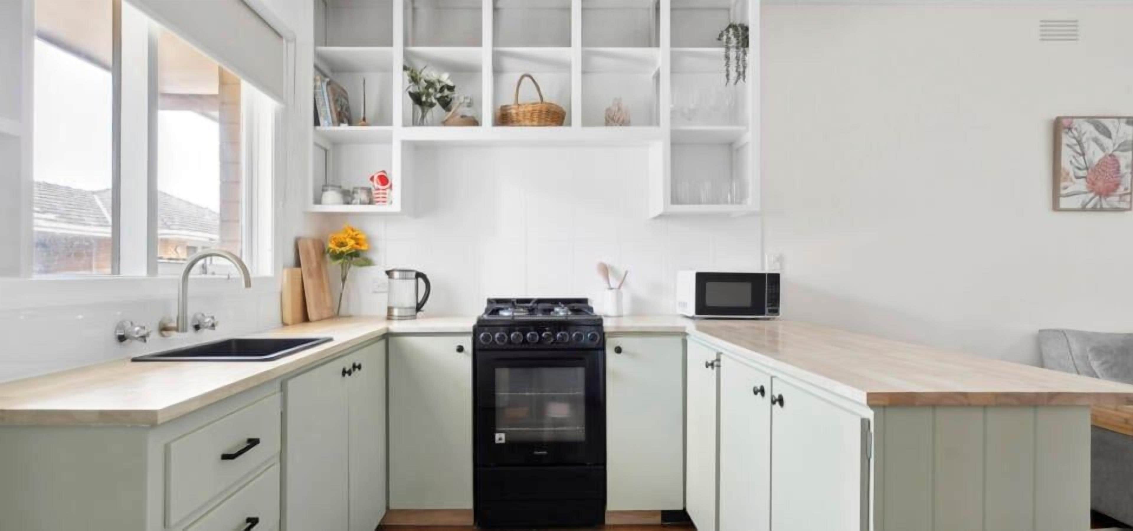A compact kitchen with a gas stove, a sink, and a microwave.