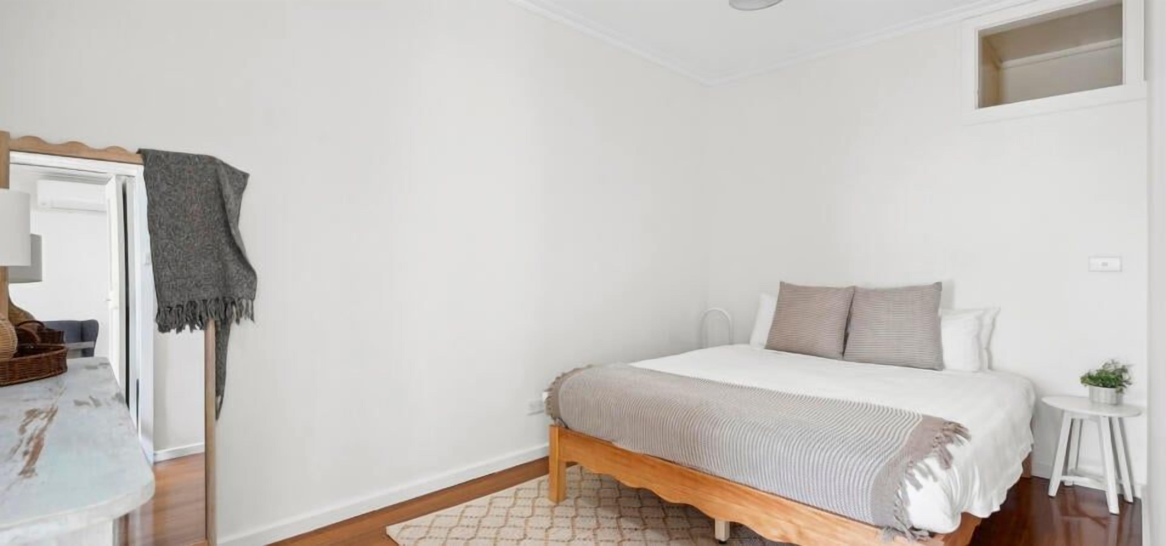 A bedroom with a bed, bedside table, and a small stool.