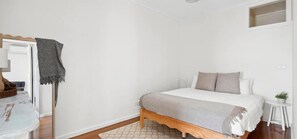 Ein Schlafzimmer mit Bett, Nachttisch und einem kleinen Hocker.