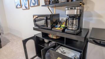 Une petite cuisine équipée d’un four à micro-ondes, d’une machine à café et de tiroirs de rangement.