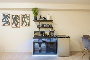 A compact kitchenette with a microwave, coffee maker, and storage drawers.