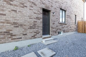 A brick building with a dark door, a small window, and a wooden fence.
