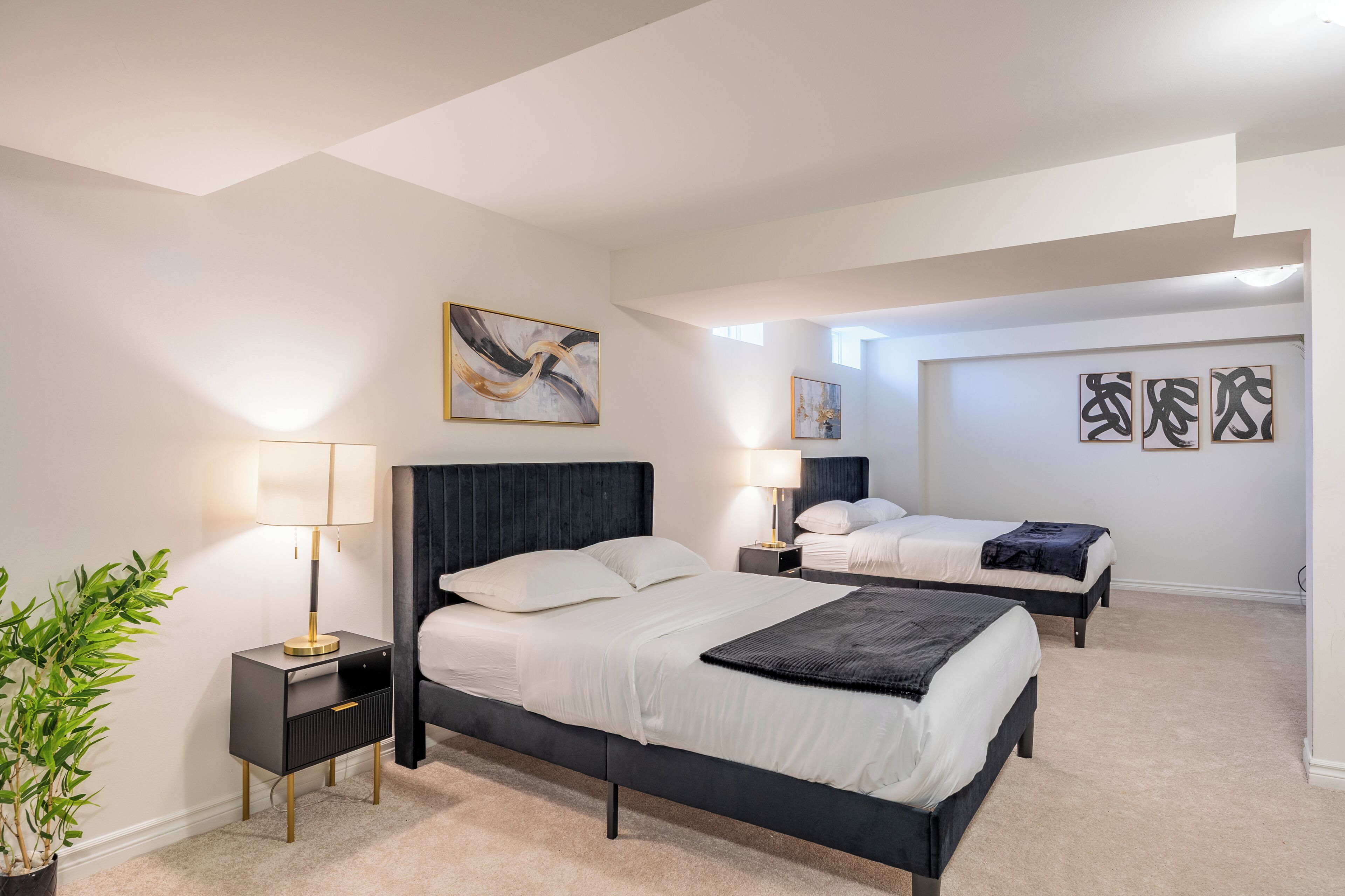 A hotel room with two beds, a large window, and artwork on the walls.