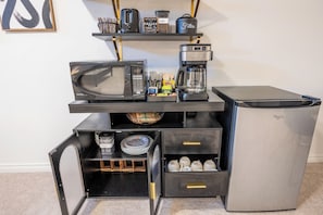 A compact kitchenette with a microwave, coffee maker, and a refrigerator.