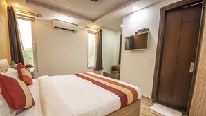 A bedroom with a bed, a TV mounted on the wall, and a wooden door. - Comfort Home Stay (New Delhi)
