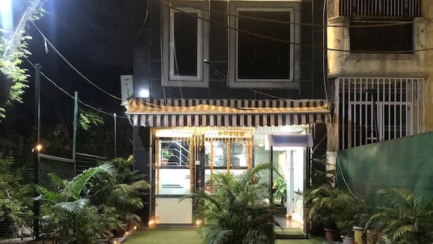 A building with a gated entrance, potted plants, and a well-lit facade. - Comfort Home Stay (New Delhi)