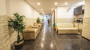A corridor with sofas and potted plants, leading to a staircase. - Comfort Home Stay (New Delhi)