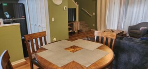 Un comedor con una mesa redonda de madera, dos sillas y un mantel tejido.