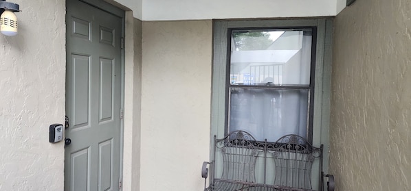 Una puerta con reja de metal, un accesorio de iluminación y una ventana con vista a una casa.